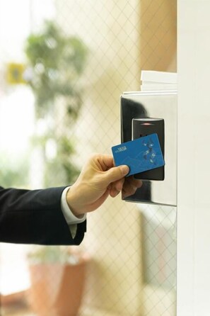 A hand holding a blue card with the text "YASSA" near a card reader. - Hotel Yassa (Mihara)