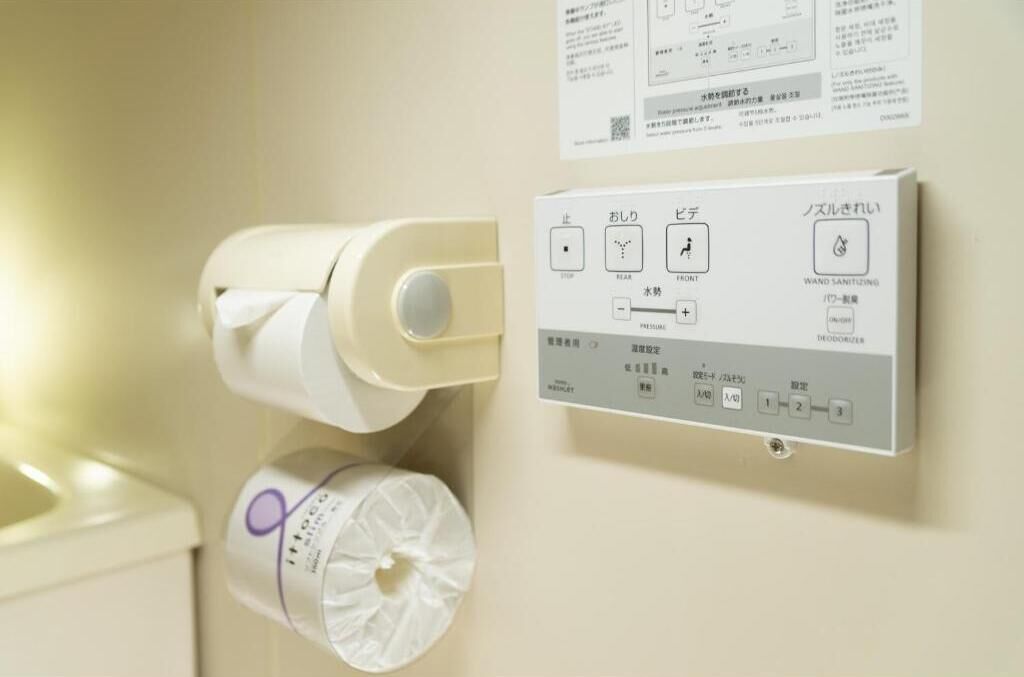 A wall-mounted toilet paper dispenser and a hand sanitizer dispenser with instructions in Japanese.