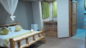 A bedroom with a wooden bed, a small desk, and a window with curtains.