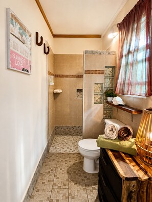 A bathroom with a toilet, shower, tiled floor, and a wooden vanity with a lamp. - Cottage  sleeps 2-3 WiFi, Pool, Kayaks Chef, staff on site (playa del carmen)