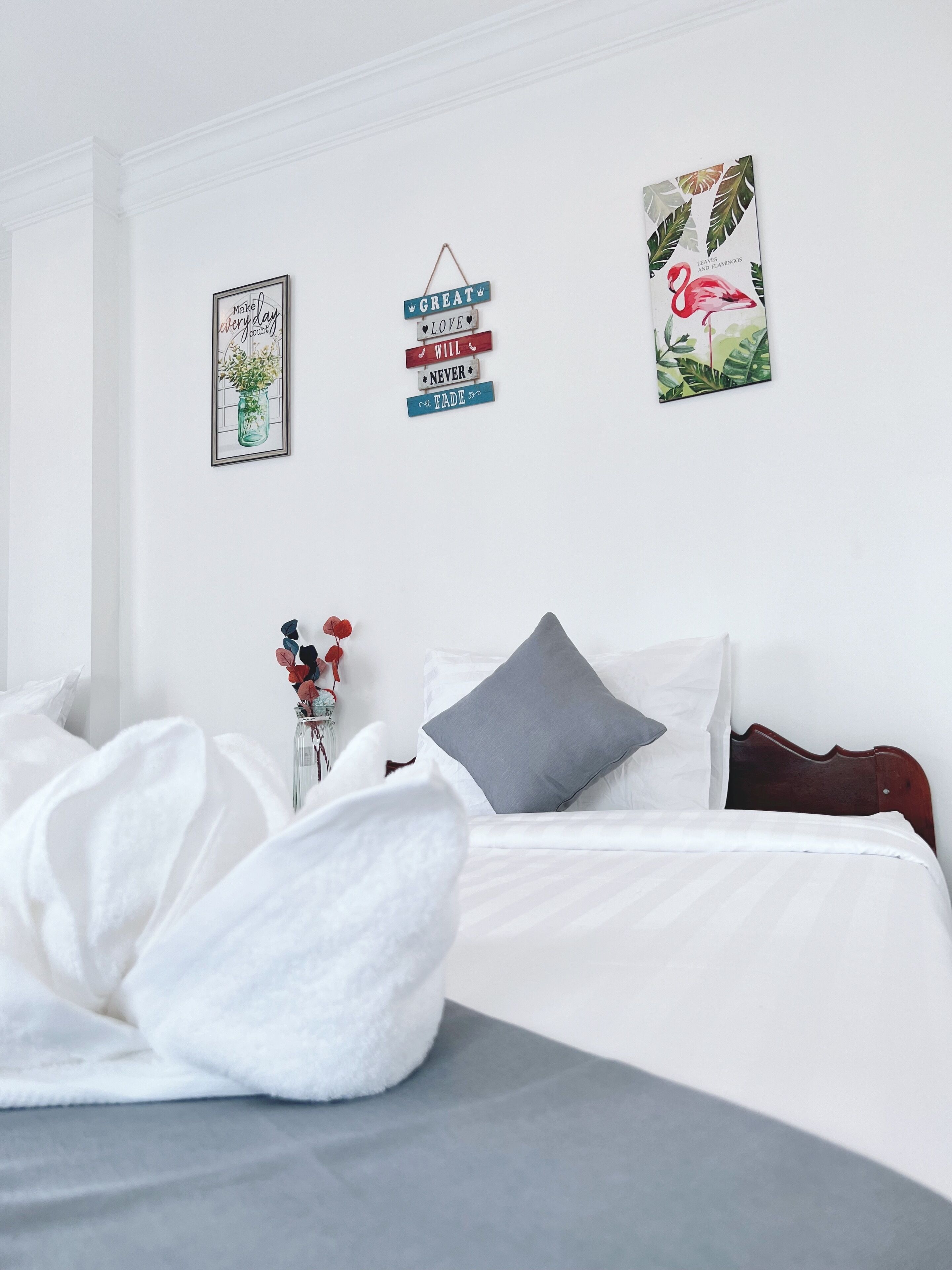 A bedroom with a bed, pillows, and wall art.