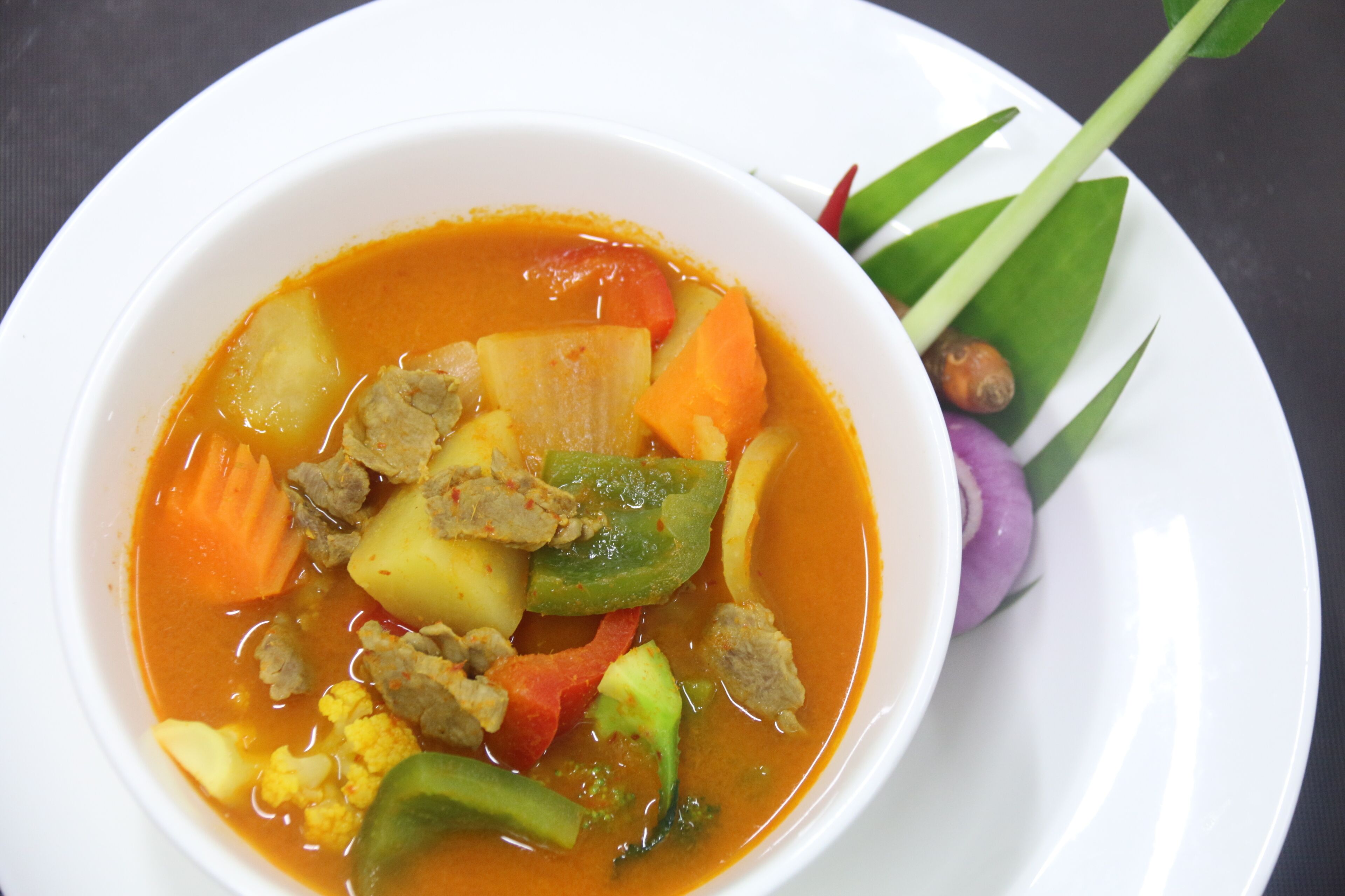 A bowl of soup with various vegetables and meat.