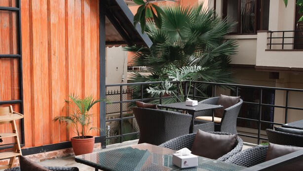 Eine Terrasse im Freien mit Korbmöbeln, einem Glastisch und Pflanzentöpfen.