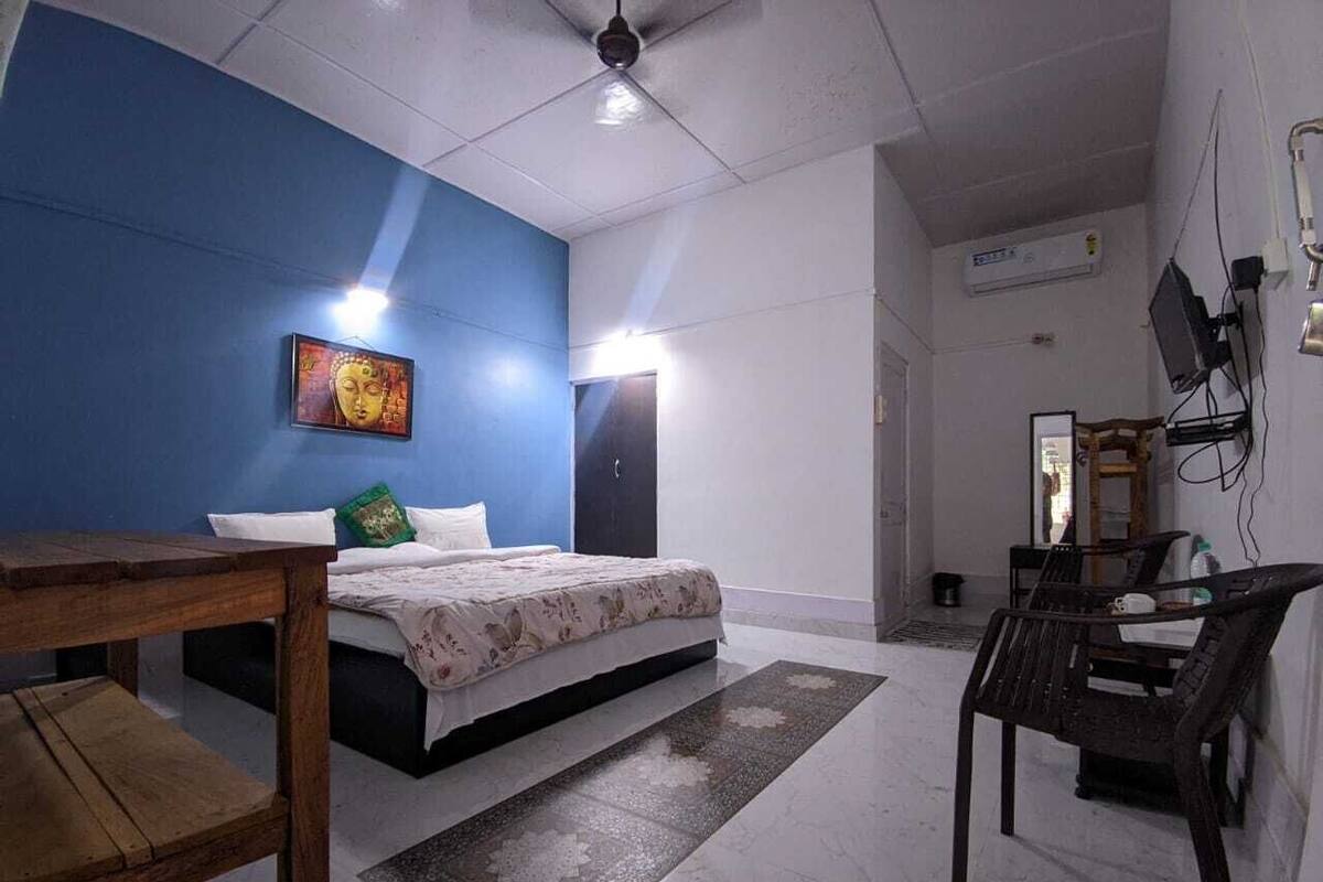 A bedroom with a bed, a wooden table, a chair, and a blue accent wall.