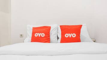 A bed with white bedding and two pillows with the word "OYO" on them.