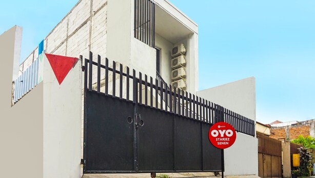 A modern building with a black gated entrance, a red triangular sign, and a circular sign with text.