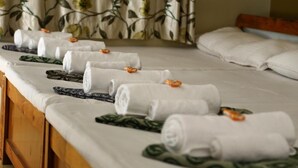 A hotel room with neatly made beds, each with a white towel and a patterned blanket. - Atithi Lodge (Ratnagiri)