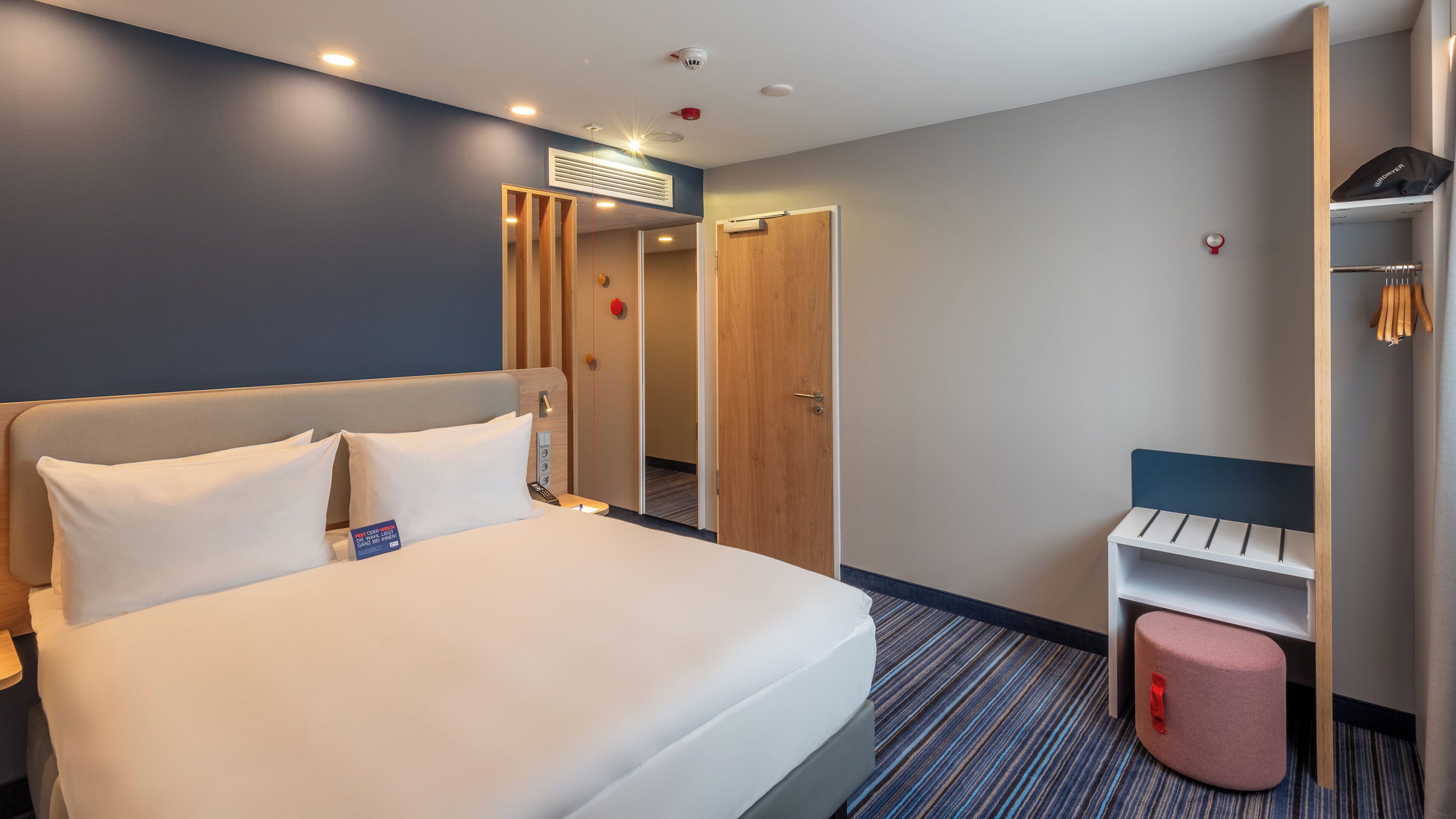 Ein Hotelzimmer mit einem Bett, einem Kleiderschrank, einem Schreibtisch und einer kleinen Sitzecke.