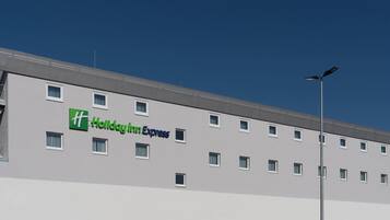A Holiday Inn Express building with a flat facade, multiple windows, and a street lamp.