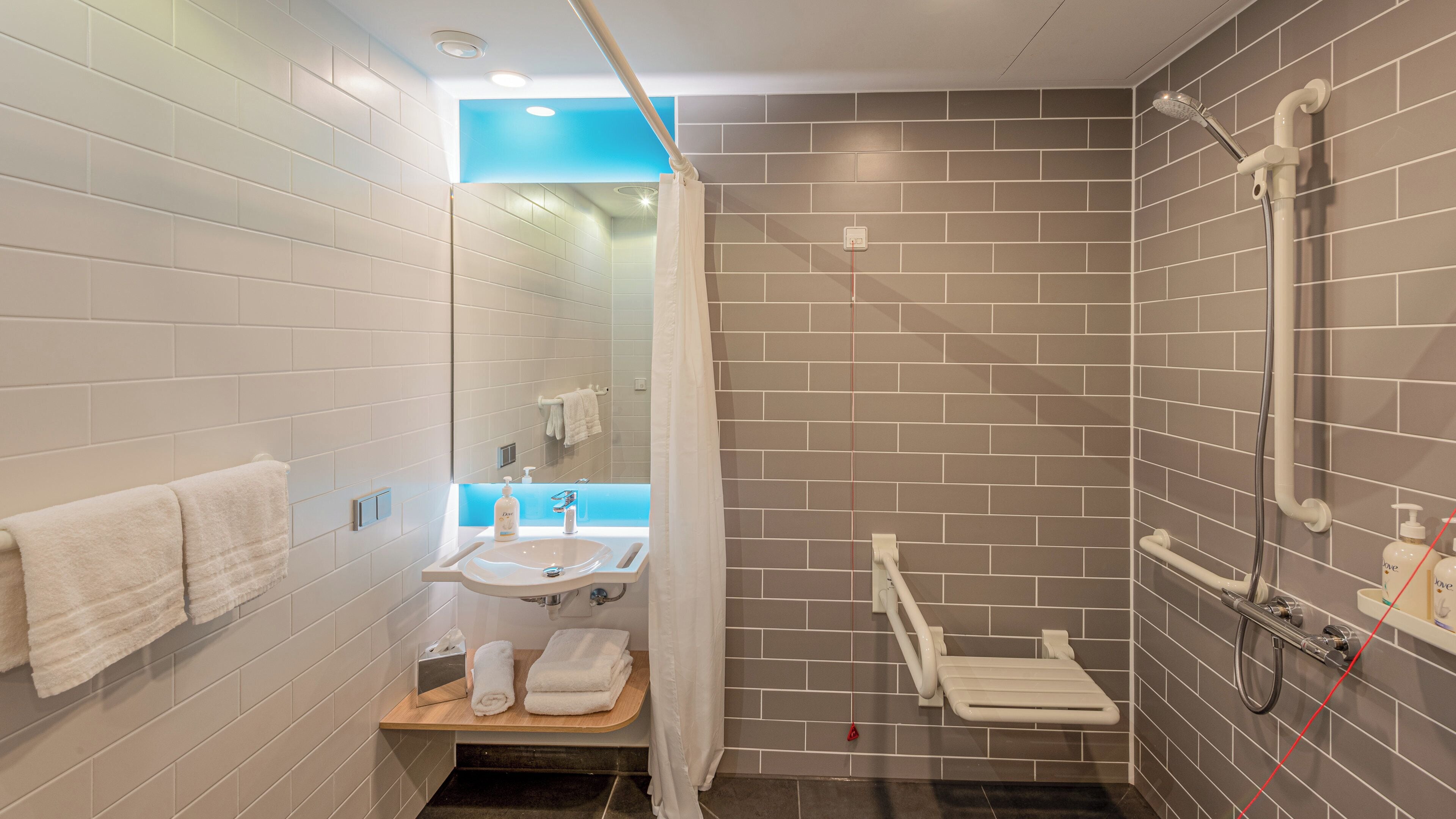 Ein modernes Badezimmer mit Dusche, Waschbecken und Spiegel.