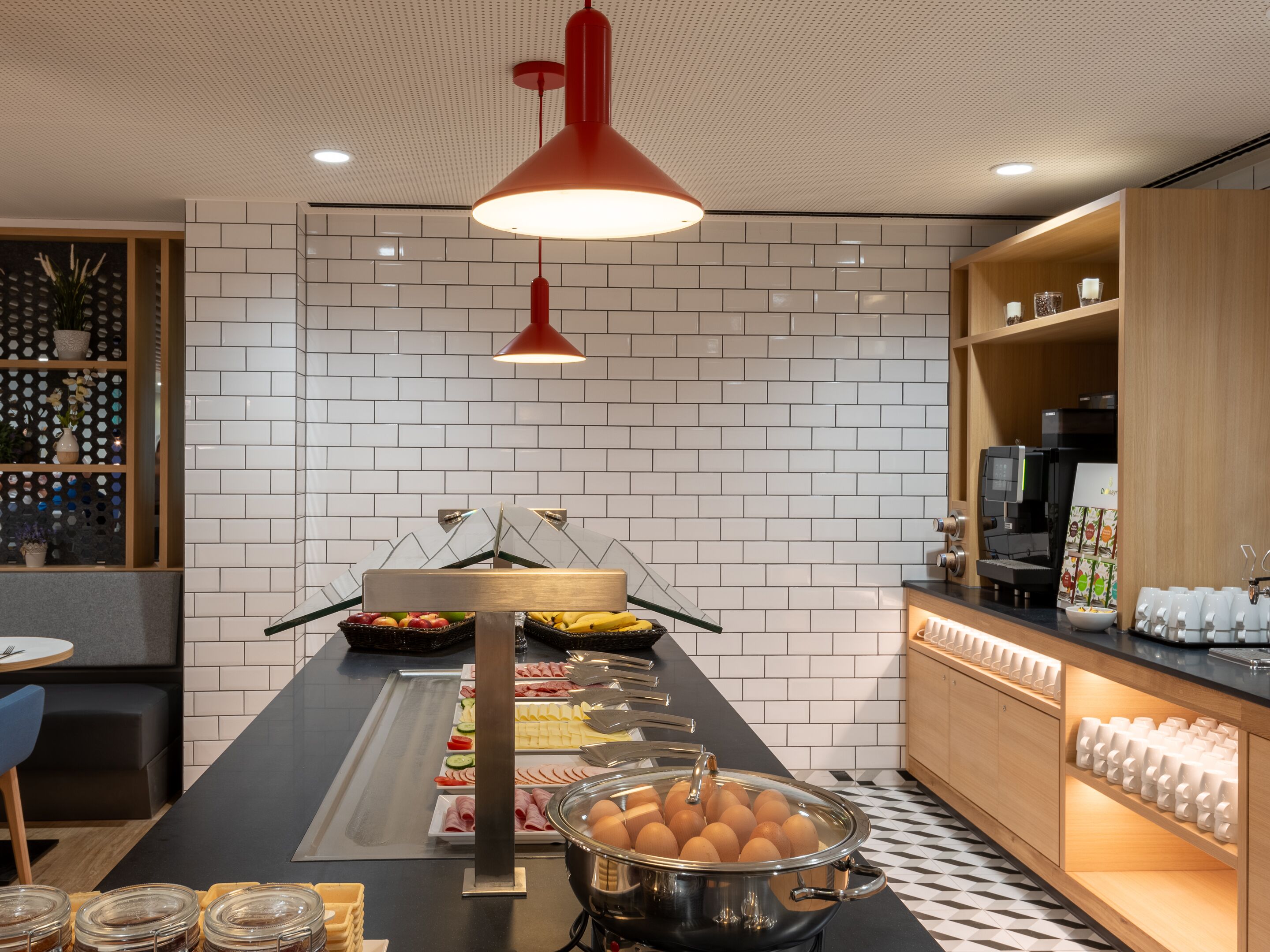 Ein reichhaltiges Buffet mit verschiedenen Speisen, einer Kaffeemaschine und einer Sitzgelegenheit mit Tisch und Stühlen.