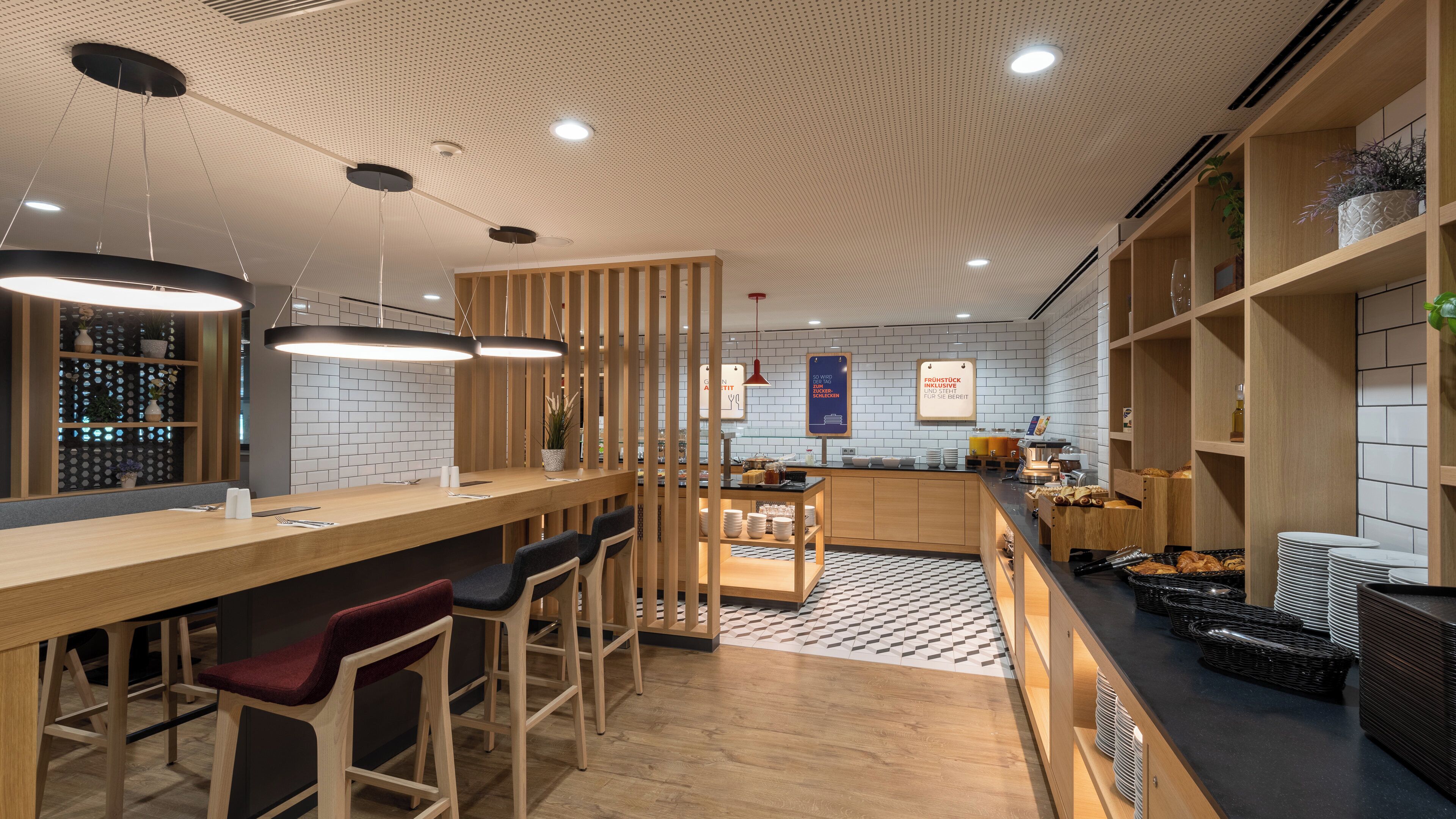 A modern kitchen with a bar area, wooden bar stools, and a patterned floor.