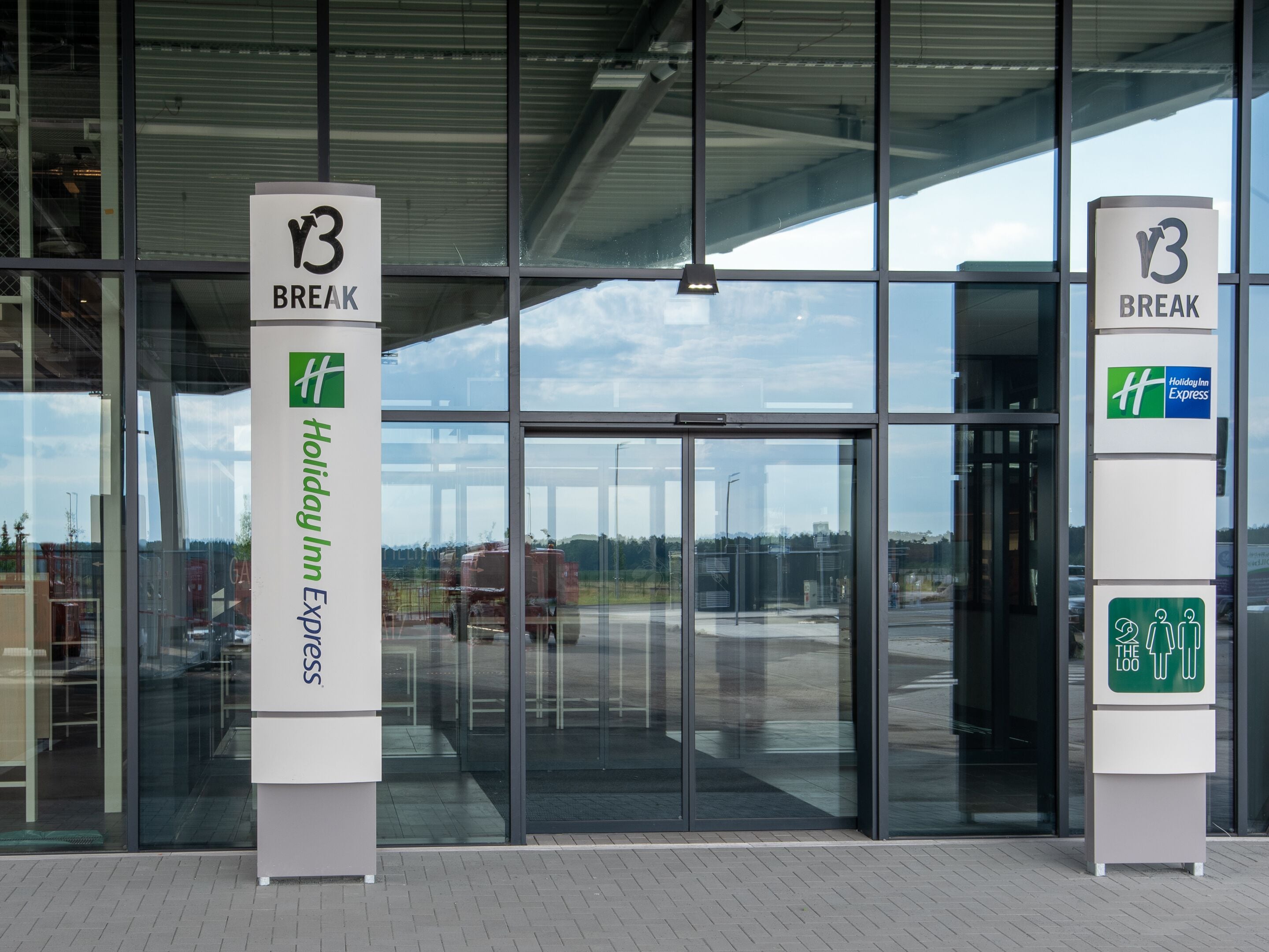 De ingang van een Holiday Inn Express, met duidelijke bewegwijzering en een moderne glazen gevel.