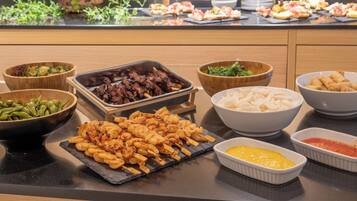 A buffet with various dishes including skewered shrimp, grilled meat, and vegetables.