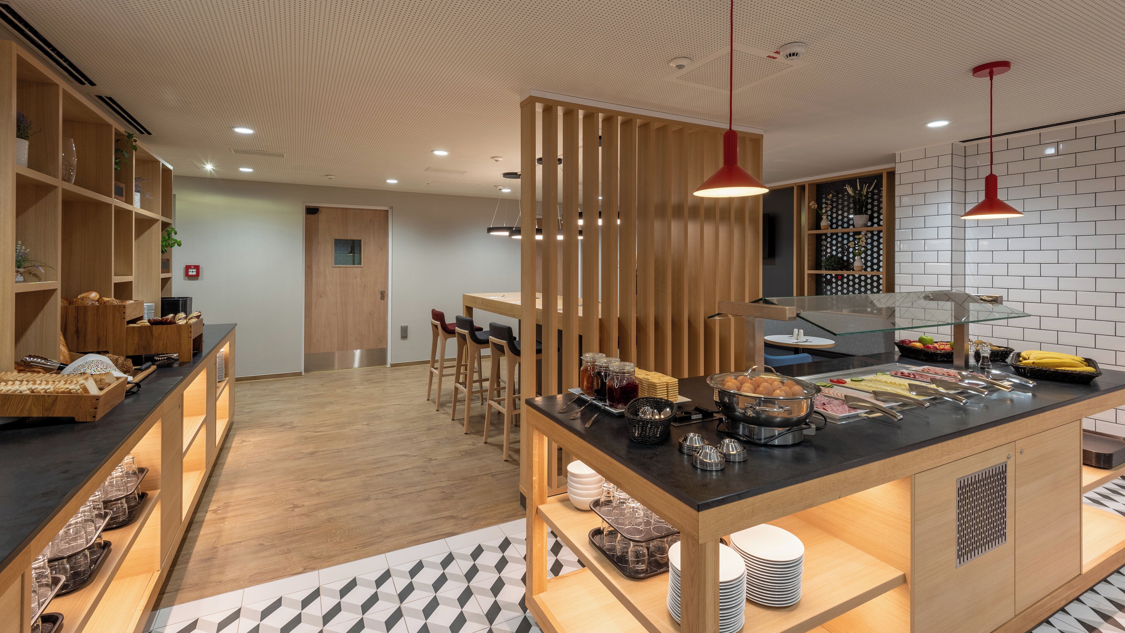 A modern kitchen with wooden cabinetry, a central island with food and drink, and a seating area with bar stools.