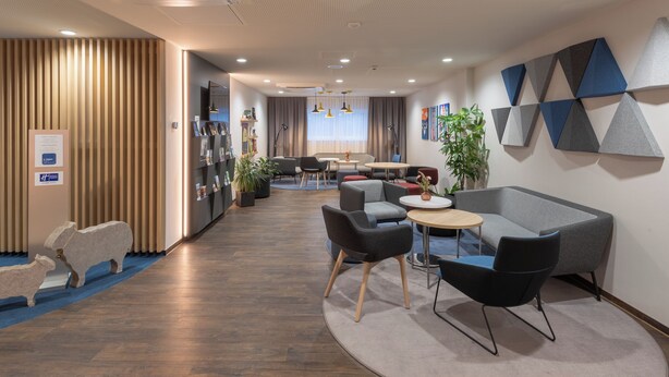 A modern office space with a reception area, seating arrangements, and a decorative wall. - Holiday Inn Express Hamburg South A7 AS42 by IHG (Egestorf)