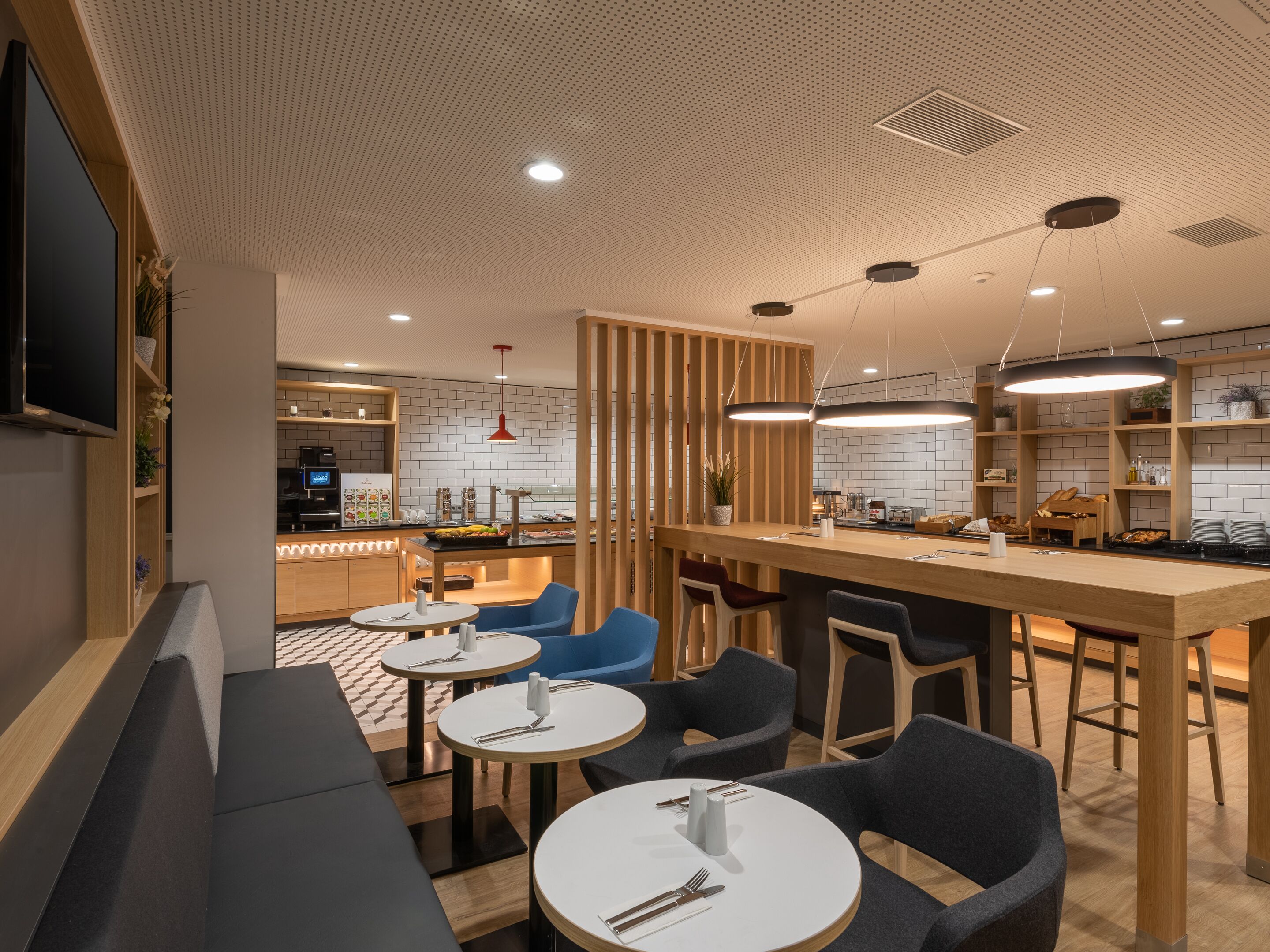 Un restaurant moderne doté d’un bar, de tables rondes et de chaises, et d’une cuisine située à l’arrière.