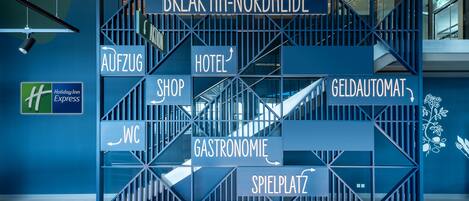 Un cartel de hotel con flechas direccionales hacia varios servicios, como el hotel, una tienda y gastronomía.