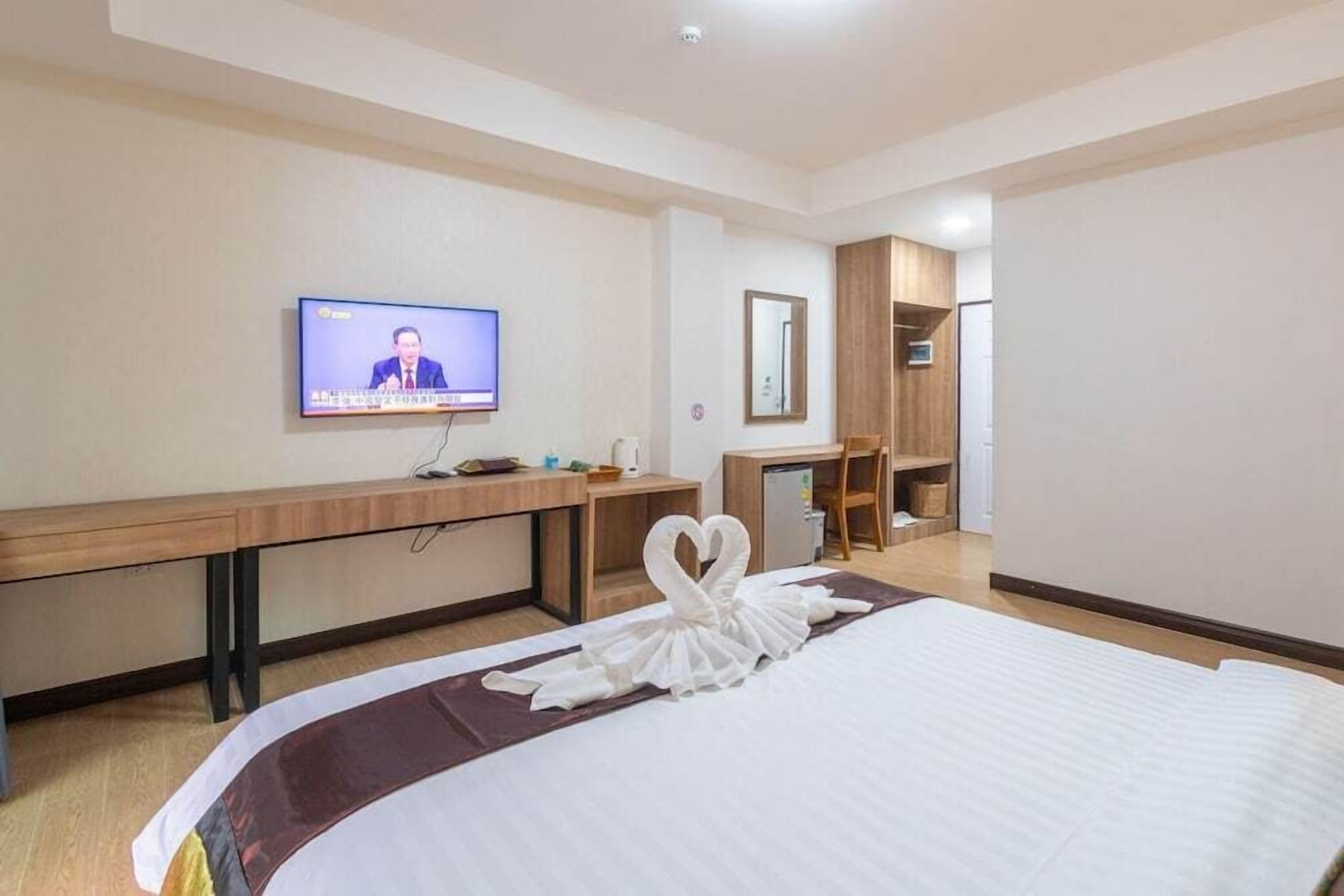 A hotel room with a bed, a desk, a television, and a mirror.