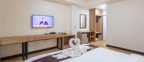 A hotel room with a bed, a desk, a television, and a mirror.