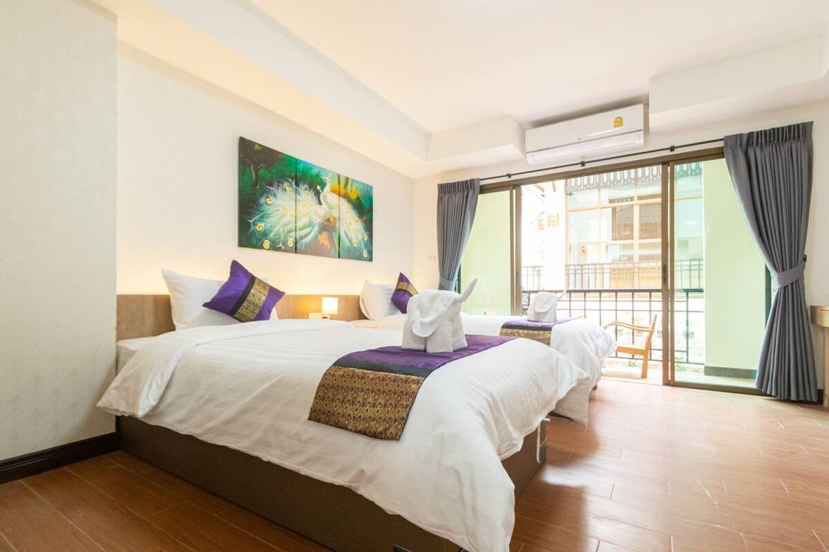 Ein Hotelzimmer mit einem großen Bett, einem Bild an der Wand, einem Balkon mit Blick und einer Schiebetür.