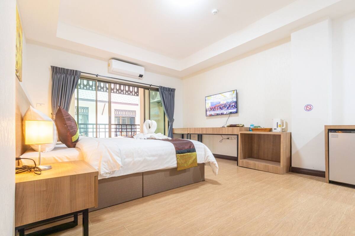 Ein Hotelzimmer mit Bett, Nachttisch, Fernseher und einer kleinen Küchenzeile.