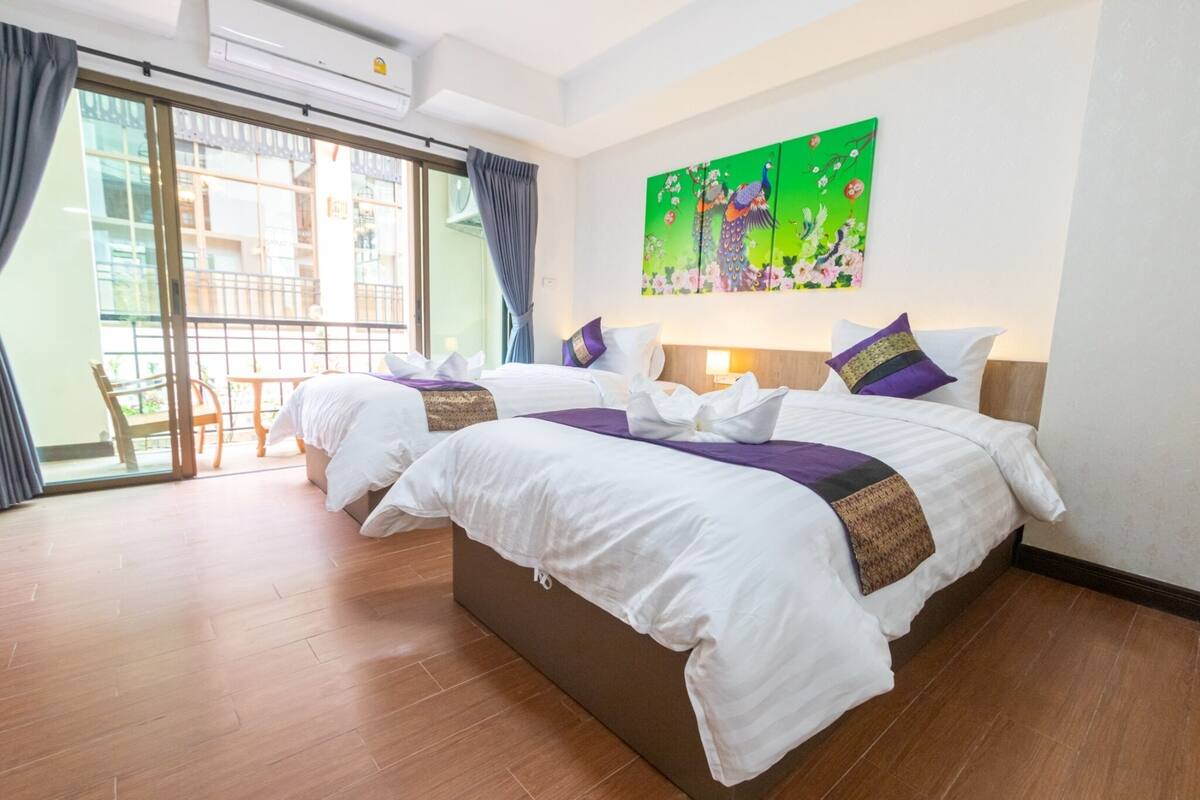 Ein Hotelzimmer mit zwei Betten, einem großen Fenster und einem Gemälde an der Wand.