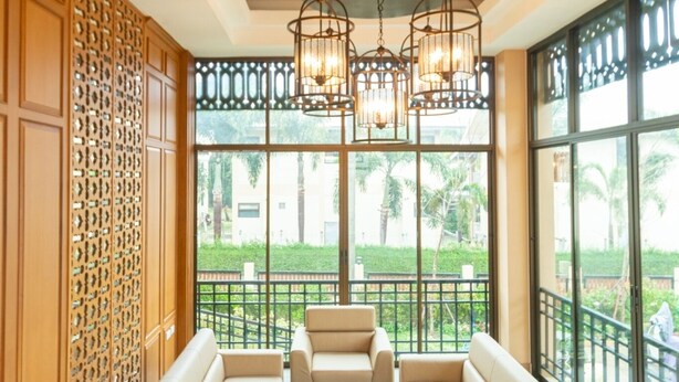 A spacious lounge area with a long sofa, a coffee table, and a chandelier. - Peacock De Pai Hotel (Pai)