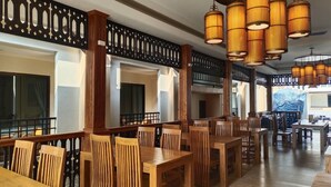 A spacious dining area with wooden tables and chairs, decorative black lattice panels, and hanging bamboo-style pendant lights. - Peacock De Pai Hotel (Pai)