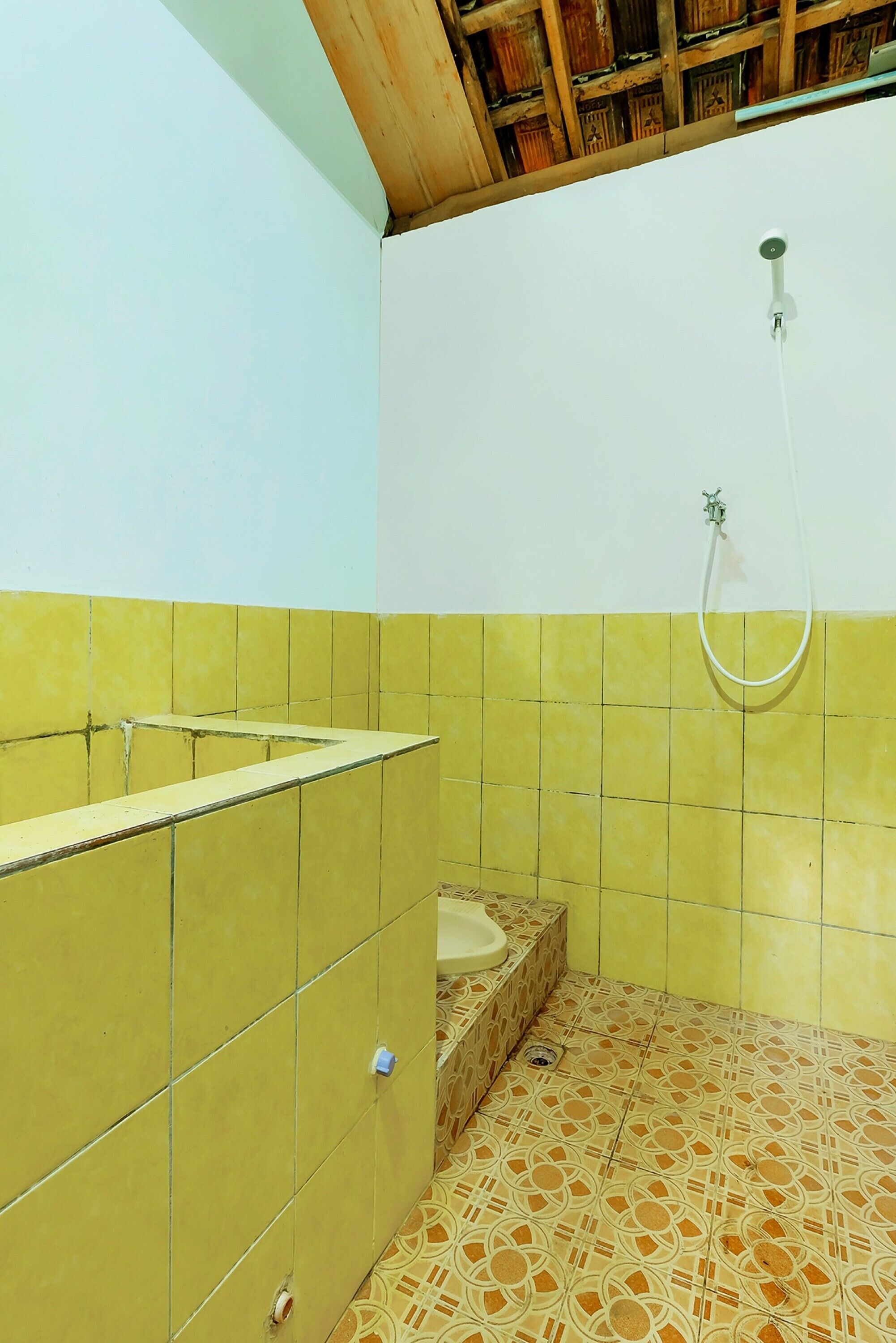 Une salle de bain avec des murs recouverts de carreaux jaunes, un lavabo et une douche.