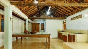 A spacious kitchen with a wooden table, cabinets, and a tiled floor.