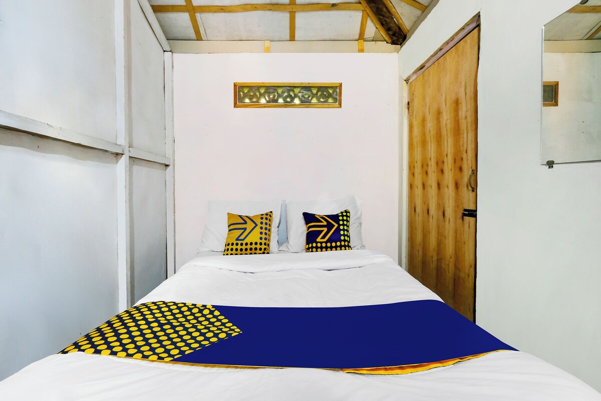 A bed with white bedding and decorative pillows, a wooden door, and a small window.