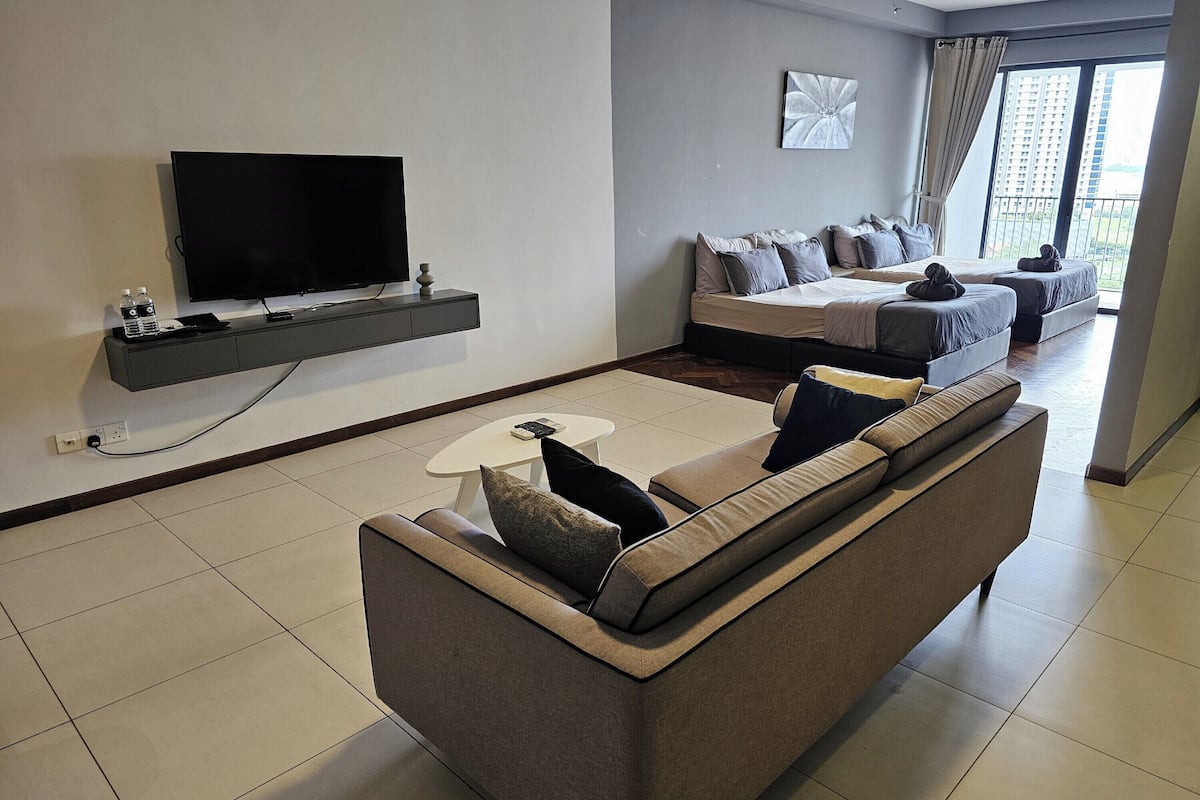 Ein modernes Wohnzimmer mit Flachbildfernseher, einer Couch, einem Couchtisch und einem Bett mit Blick auf eine Stadtlandschaft.