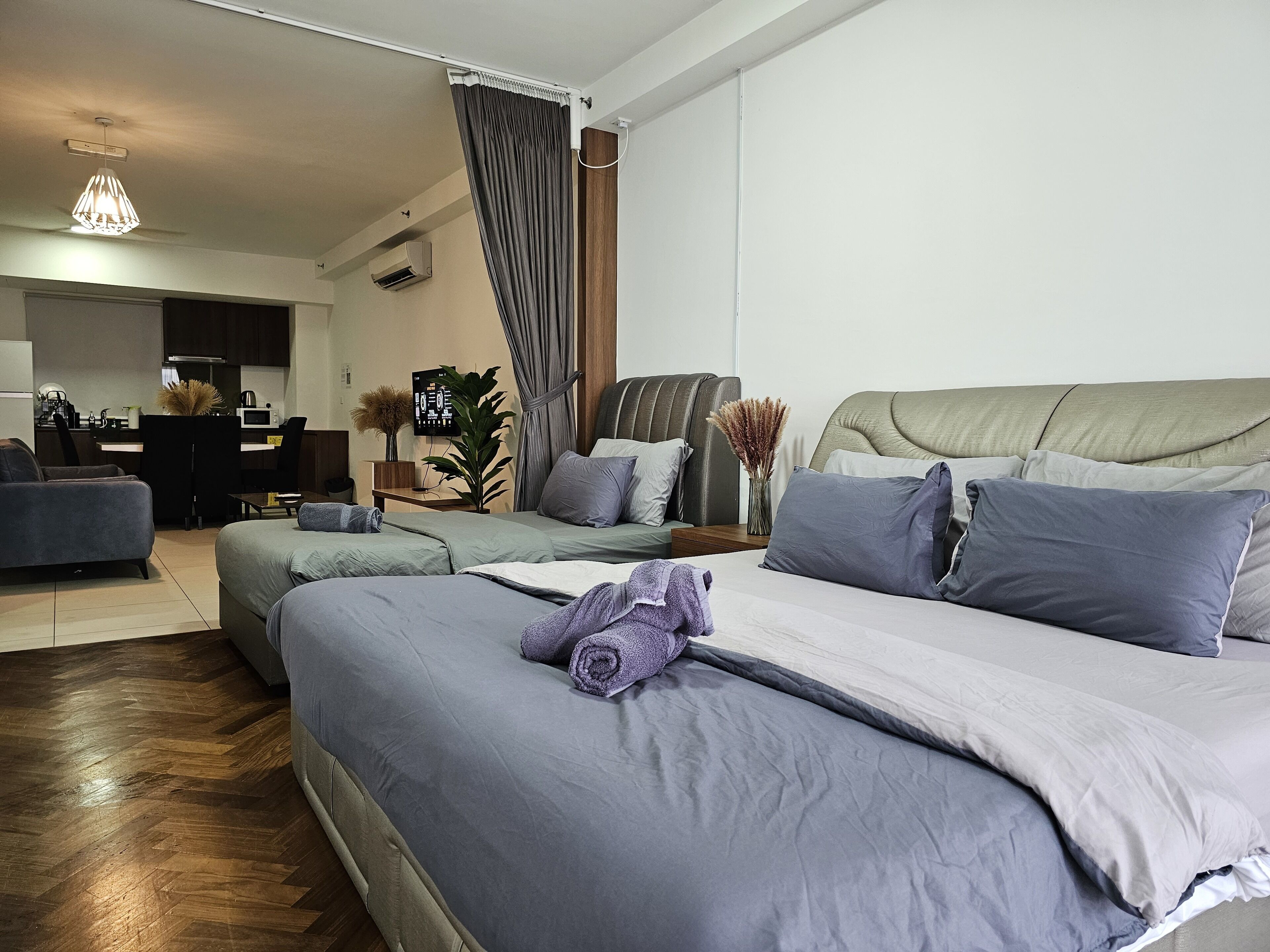 A modern bedroom with a large bed, a sofa, a desk, and a dining area.