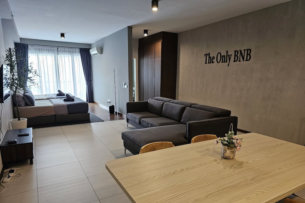 Ein modernes Wohnzimmer mit einer Couch, einem Esstisch und einem an der Wand befestigten Schild mit der Aufschrift "The Only RNB".