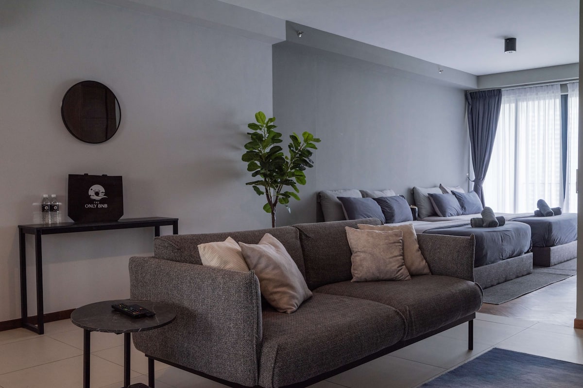 Ein modernes Wohnzimmer mit einem grauen Sofa, einem kleinen runden Tisch und einer Topfpflanze.