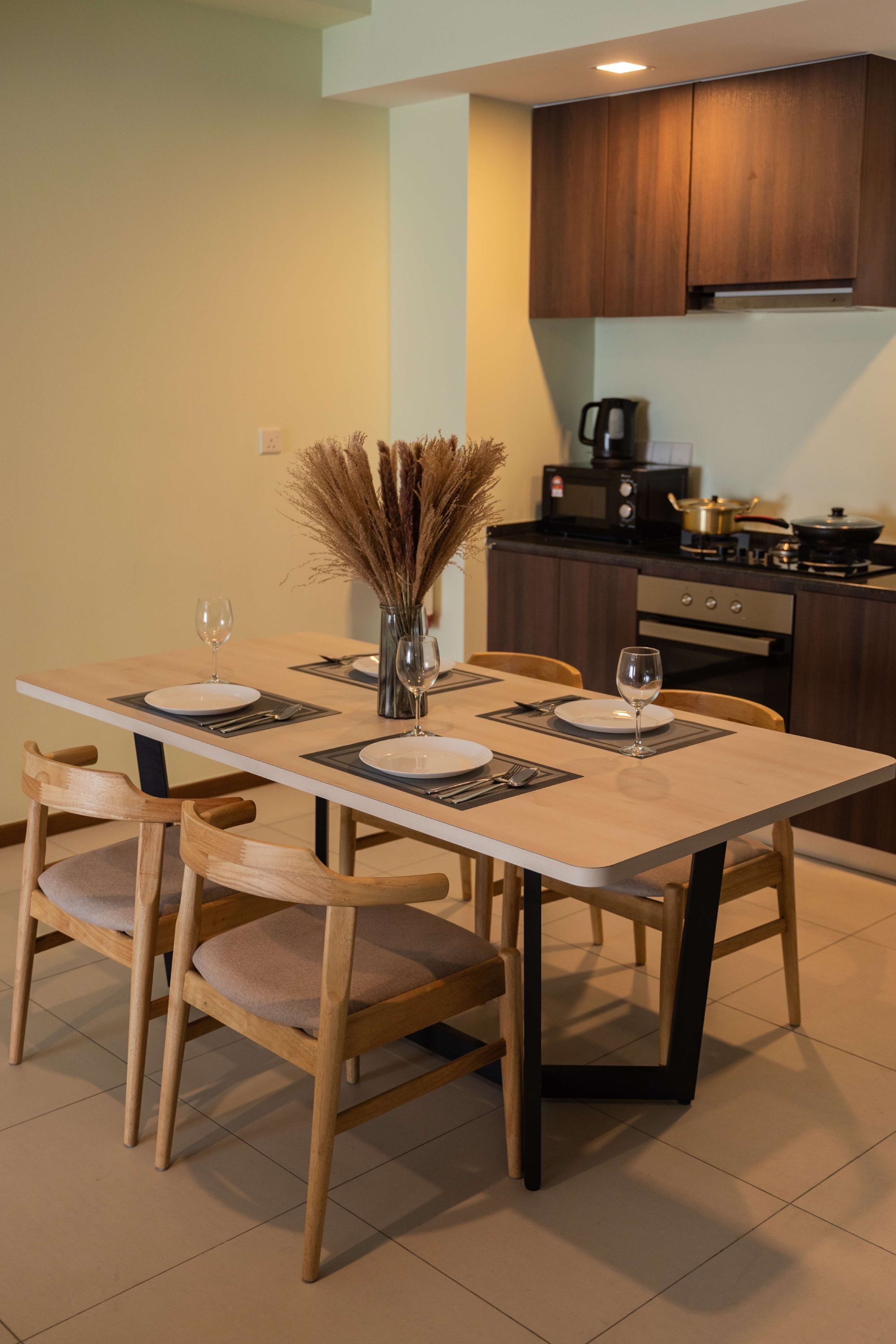Una cocina moderna con armarios de madera, una mesa de comedor lista para cuatro personas y un jarrón con plantas secas.