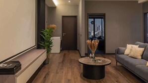 Una sala de estar moderna con un sofá gris, una mesa redonda de centro y vistas de la ciudad a través de un ventanal grande.