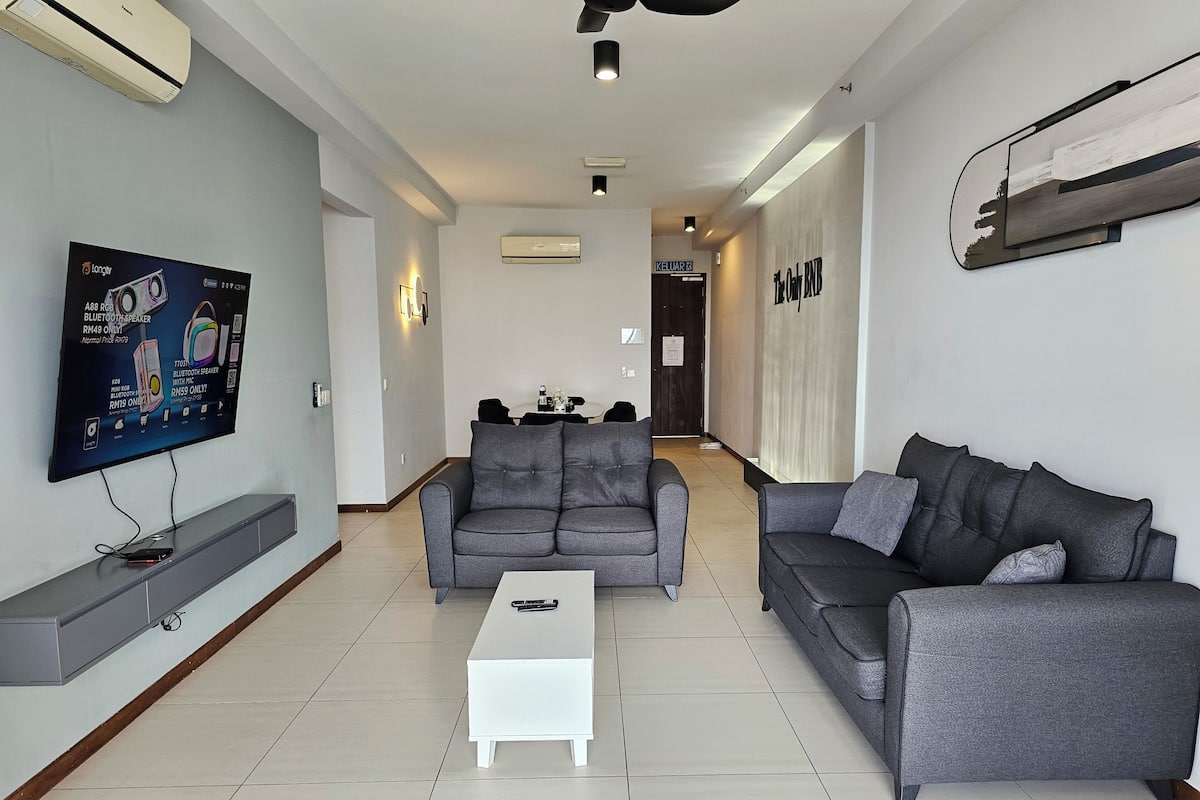 Ein modernes Wohnzimmer mit zwei grauen Sofas, einem weißen Couchtisch und einem flachbildfernseher an der Wand.