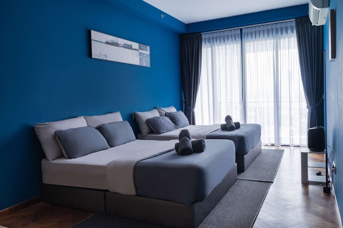Ein modernes Hotelzimmer mit zwei Betten, einem großen Fenster mit durchsichtigen Vorhängen und einer Wand-Klimaanlage.