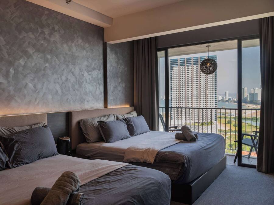 Una habitación de hotel moderna con dos camas, un ventanal y vistas a la ciudad, y un balcón con vistas al horizonte urbano.