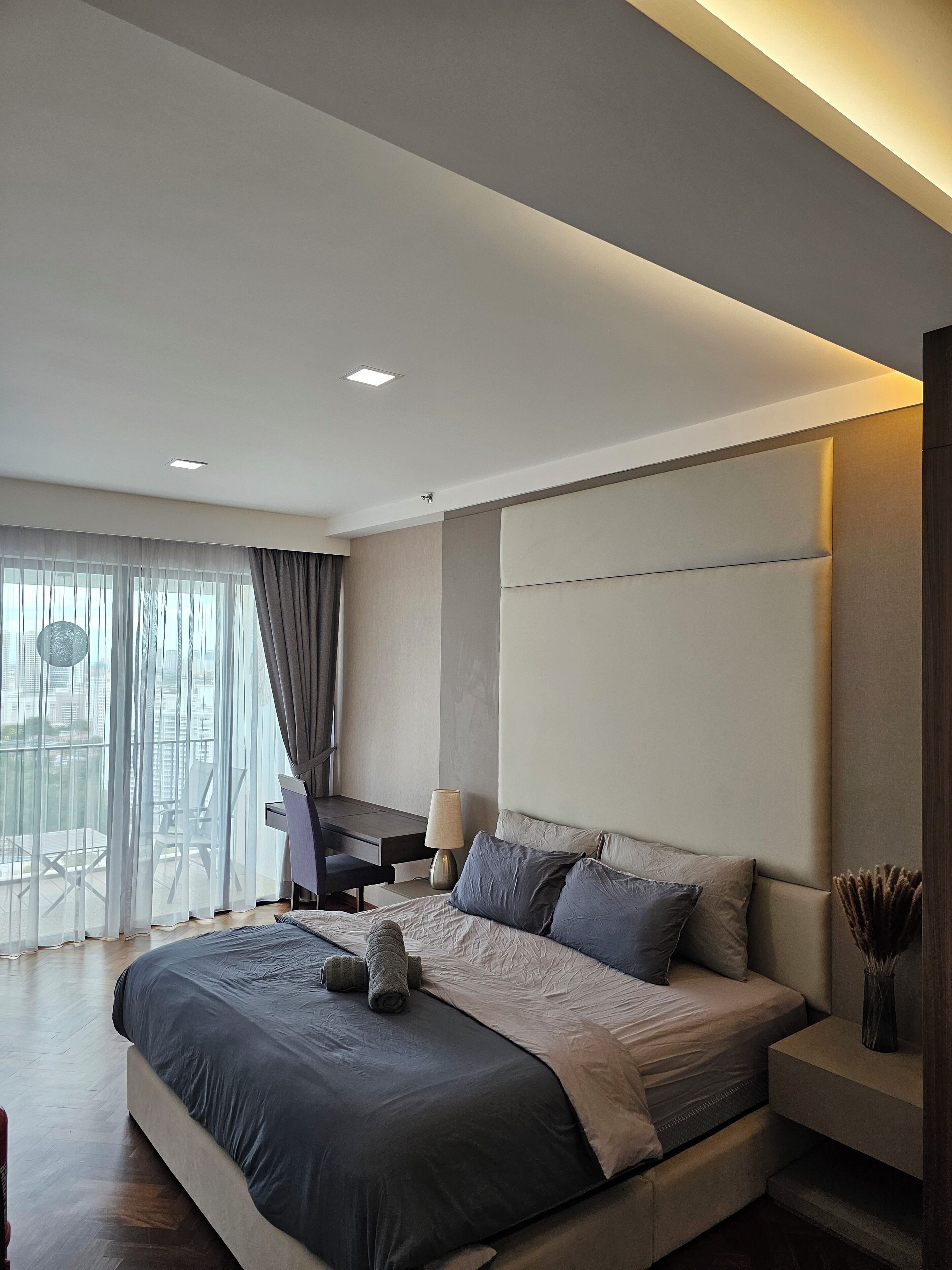 A modern bedroom with a large bed, a desk, and a chair.