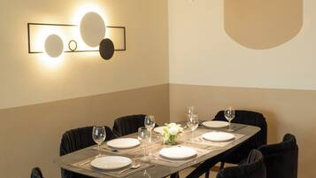 A dining area with a rectangular table set for six, surrounded by six black chairs with gold accents.