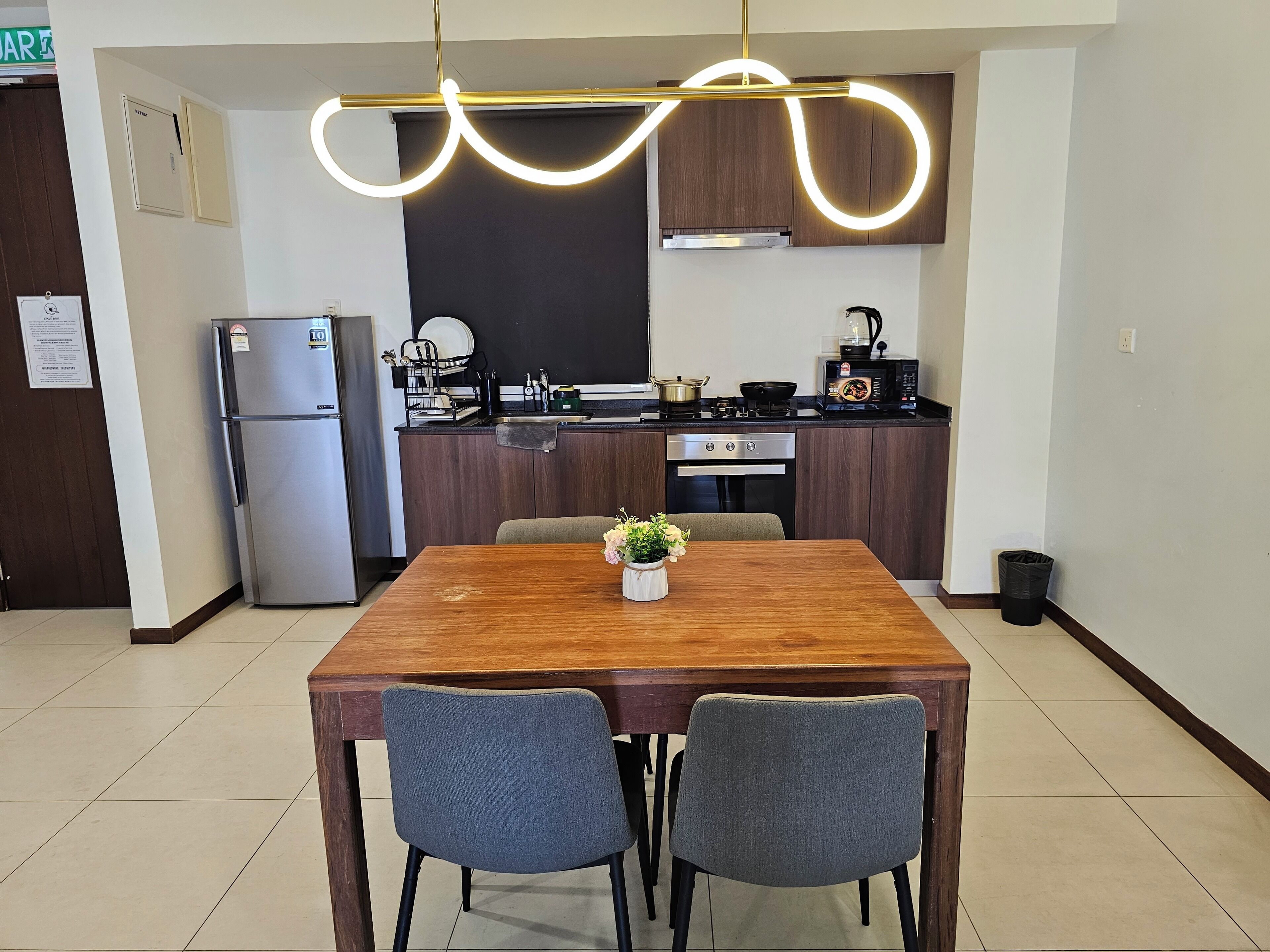 A modern kitchen with a wooden table and two chairs, a refrigerator, a microwave, and a sink.