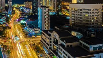 A nighttime cityscape with illuminated high-rise buildings and a busy multi-lane road.