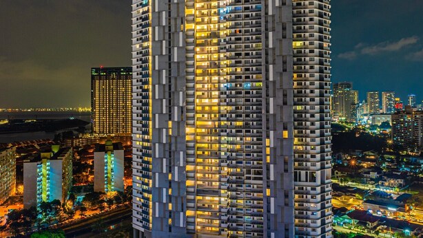 Un edificio alto con varios pisos, rodeado de otros edificios y una calle con mucho movimiento.