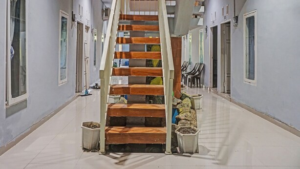 Ein Korridor mit einer Holztreppe, Fliesenboden und mehreren Türen.
