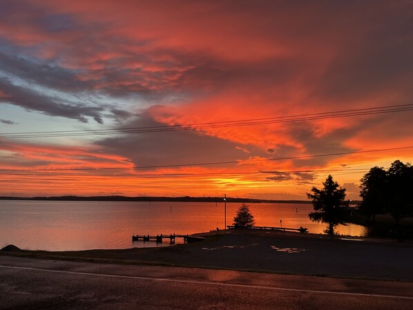 A sunset over a body of water with a dock and trees in the foreground.