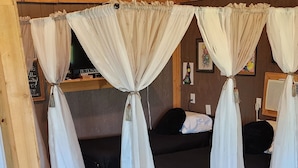 Une chambre avec deux lits, chacun agrémenté de rideaux blancs, un plancher en bois et un plafond en bois.