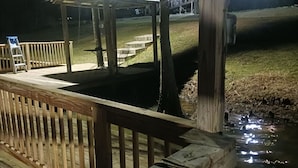 Une terrasse en bois avec une rambarde, un espace salon abrité et un petit élément décoratif aquatique.